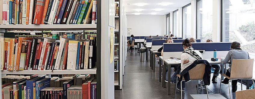 Studierende sitzen an Tischen in einer Bibliothek und lernen.
