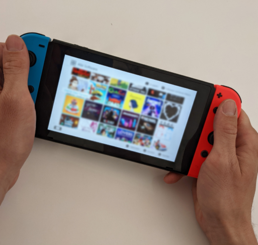 two hands holding a Nintendo Switch