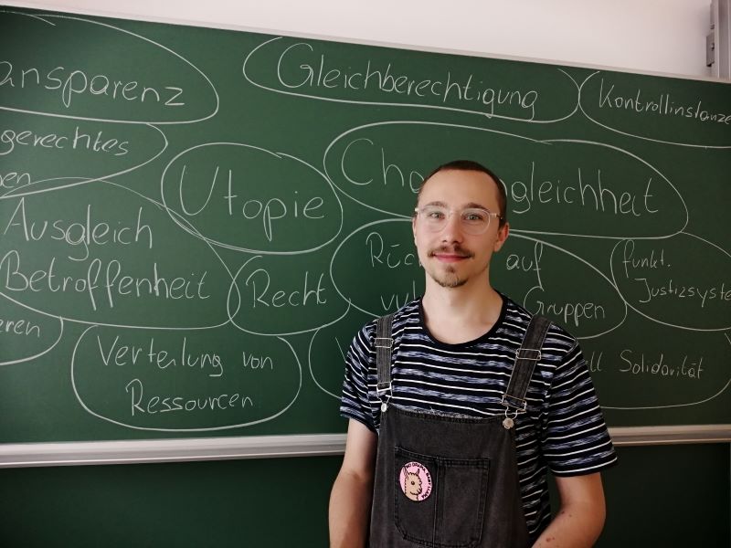 Projektmitarbeiter Jakob Steinbachner vor einer Tafel mit Begriffen zum Thema des Projektes